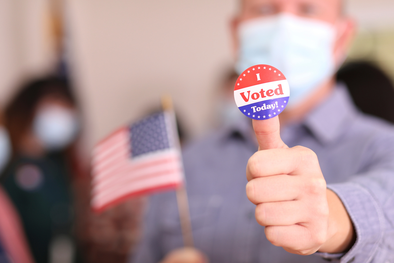 Man votes in USA election wearing mask and I Voted sticker.